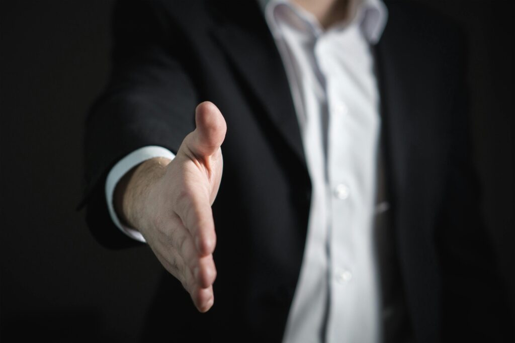 Close-up of a businessman extending hand for a handshake, symbolizing agreement and partnership.